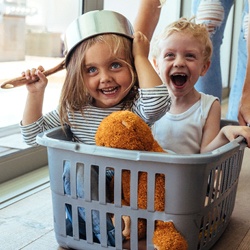 parent pushing kids around in a laundry basket