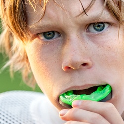 boy inserting green mouthguard