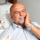 Older male dental patient holding cheek